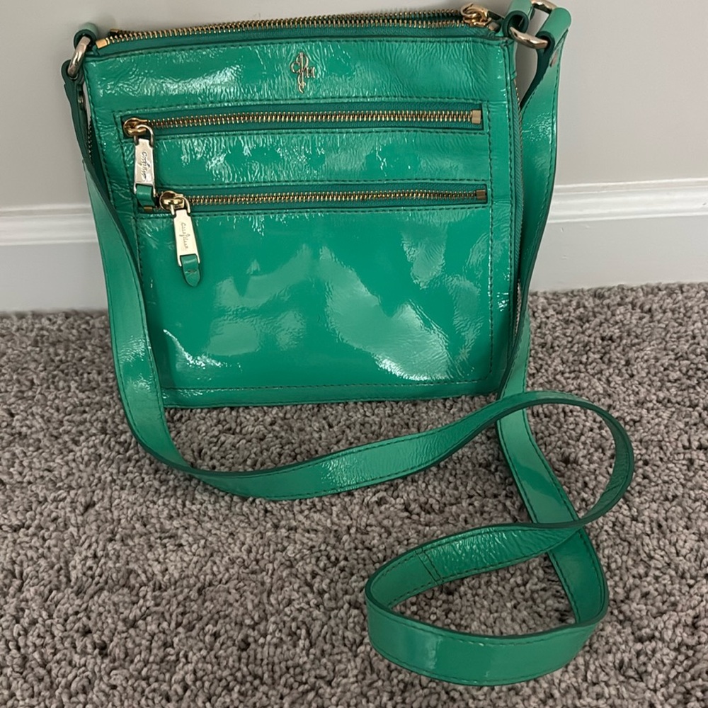 Cole Haan Jitney Sheila expandable crossbody bag in a green  patent leather